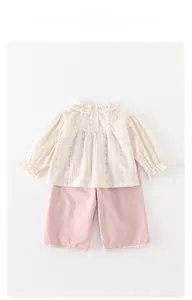 Detailed view of ruffle collar floral blouse and lace trim on pink trousers
