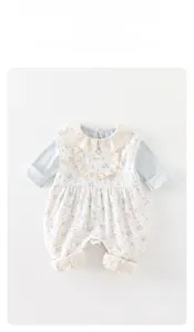 Detail of floral baby bodysuit with white lace collar and blue patchwork sleeves