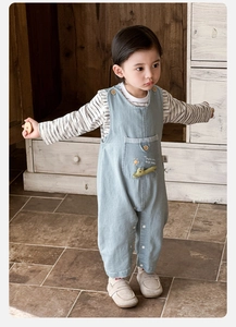 Close-up of baby denim overalls set featuring cartoon crocodile embroidery and striped shirt