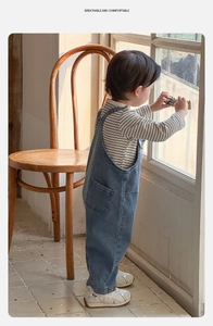 Détail de la salopette en jean pour bébé et du t-shirt rayé dans un cadre cosy