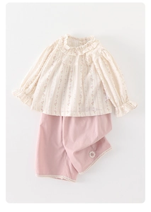 Close-up of floral baby girl blouse with ruffled collar and lace-trimmed pink shorts