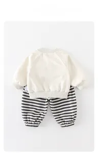 Flat lay of beige baby long-sleeved sweatshirt and black and white striped joggers set