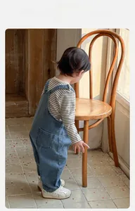 Détail du t-shirt rayé pour bébé et de la salopette en jean au tissu respirant et confortable