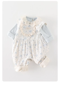 Detailed close-up of floral baby jumpsuit with lace collar and handmade label tag