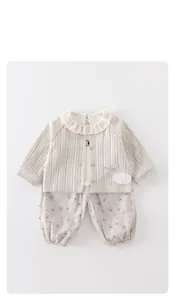 Nahaufnahme der cremefarbenen Strickjacke mit Spitzenkragen und geblümten Baby-Leggings