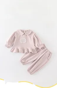 Détail d'une tenue rose pour bébé fille avec col Peter Pan et ourlet à volants décoré