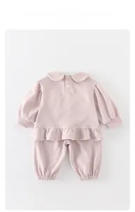 Détail d'ensemble rose pour bébé fille avec col Peter Pan et ourlet à volants élégant