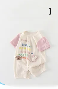 Detail eines Baby-Baumwoll-Stramplers mit Bärenstickerei und bunten FUN SMILE Aufdrucken