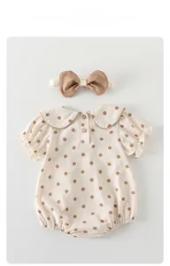 Detail of baby summer bodysuit with brown polka dots and matching headband on grey backdrop