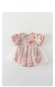 Dettaglio pagliaccetto neonata con stampa floreale, gonna in tulle rosa e maniche a sbuffo
