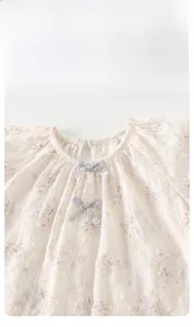 Detailaufnahme des Baby-Oberteils mit Blumenmuster, grauer Satinschleife und Streifentextur