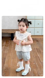 Detail of floral sleeveless top with ruffled collar and blue bloomers on child model