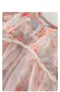 Dettaglio della tutina per neonata con stampe floreali di rose e ricami in pizzo rosa