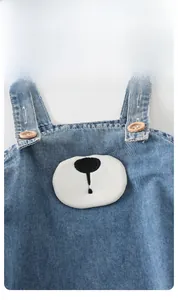 Close-up of light blue denim baby jumpsuit with animal patch and wooden buttons