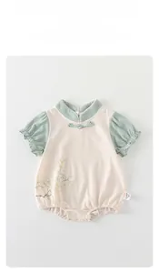Detail of baby romper featuring Chinese frog button and floral print on cotton fabric