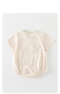 Detail of short-sleeved baby romper with green ribbed collar and breathable fabric texture