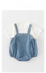 Flat lay of white baby t-shirt and light blue denim overall set with visible stitching