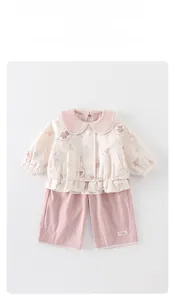 Détail de la veste cardigan à fleurs pour bébé et du pantalon rose avec bordure dentelle