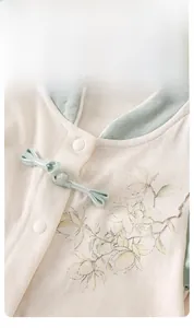 Détail d'un barboteuse pour bébé avec bouton chinois traditionnel et motif floral
