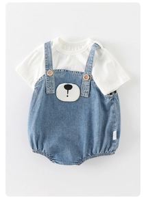 Detail of baby denim jumpsuit with cute cartoon bear patch and soft cotton white t-shirt