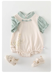 Detail view of baby onesie with Chinese frog buttons and magnolia flower pattern