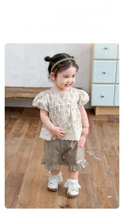 Close-up of girls' floral puff sleeve top with lace trim and ruffled khaki cotton shorts