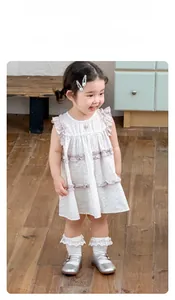 Détail d'une robe fleurie pour bébé fille avec bordure en dentelle et volants violets