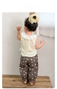 Detail of baby summer set featuring lace collar beige top and floral print brown pants