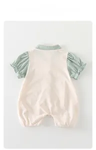 Détail d'une barboteuse en coton pour bébé avec manches à volants et col vert doux