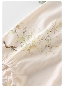 Detailed close-up of floral print and elastic cuff on baby cream bodysuit sleeve