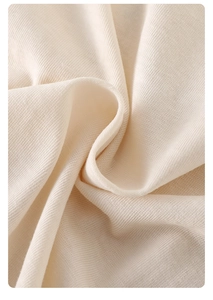 Close-up of soft cream knitted cotton fabric showing fine texture on baby bodysuit