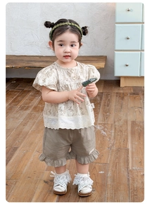 Detail view of toddler floral puff sleeve top with lace trim and brown ruffle shorts