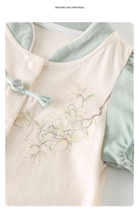 Détail d'une grenouillère traditionnelle pour bébé avec bouton grenouille et motif magnolia