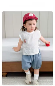 Detail of toddler summer outfit with striped tank top, denim shorts, and red baseball cap