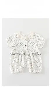 Détail de barboteuse bébé à fleurs avec col en dentelle délicate et volants sur blanc