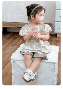 Detail view of floral puff sleeve shirt with lace trim and olive green ruffled shorts