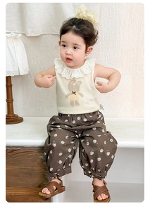 Close-up of the elegant lace collar and cute brown bunny print on the beige baby top