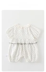 Détail d'un barboteuse bébé à fleurs avec col en dentelle et volants à la taille