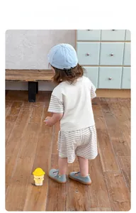 Flat lay of boys beige and striped cotton T-shirt with matching shorts and a blue sun hat