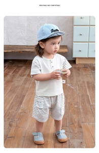Detail of boys summer set with beige cotton t-shirt and striped shorts on child model
