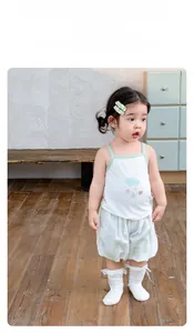 Detail of girls' summer set featuring a white tank top with cloud print and green trim