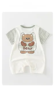 Detail of soft cream baby romper with green plaid sleeves and cute cartoon bear print