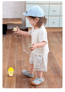 Detail of boys summer beige cotton t-shirt and striped shorts set in a home setting