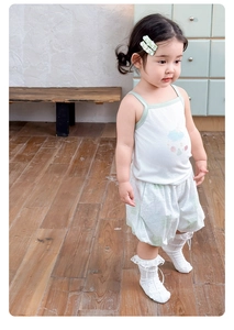 Detail of girls summer set with white tank top and green checkered shorts in a cozy setting
