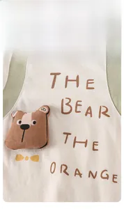 Close-up of beige knitted baby bodysuit featuring a 3D plush bear and text detail