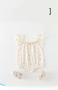 Détail d'un body fleuri pour bébé avec bretelles en dentelle et sandales assorties