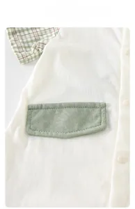 Detail of white cotton baby bodysuit with green pocket and breathable knit fabric texture