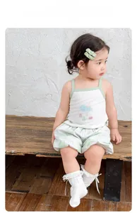 Detail of girls' summer set with white ribbed tank top and green floral shorts