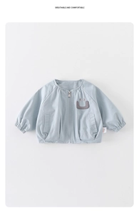 Détail d'une veste bleu clair pour bambin avec tissu respirant et écusson smiley brodé