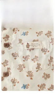 Dettaglio camicia neonato in cotone con stampe di anatre, bottoni legno e tasca sul petto